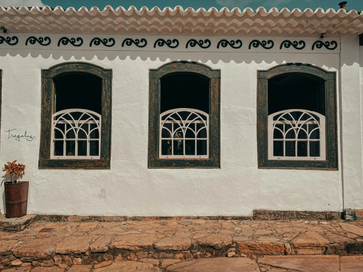 a building with three windows and two flower boxes on the ground