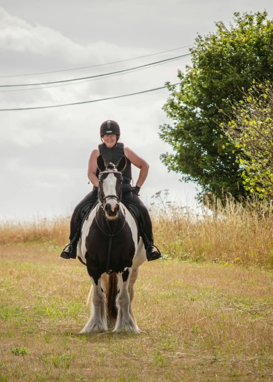 a woman wearing a helmet and riding on top of a white and brown horse