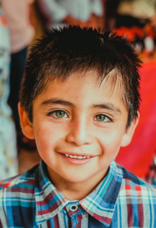 a small boy smiling in a blue plaid shirt