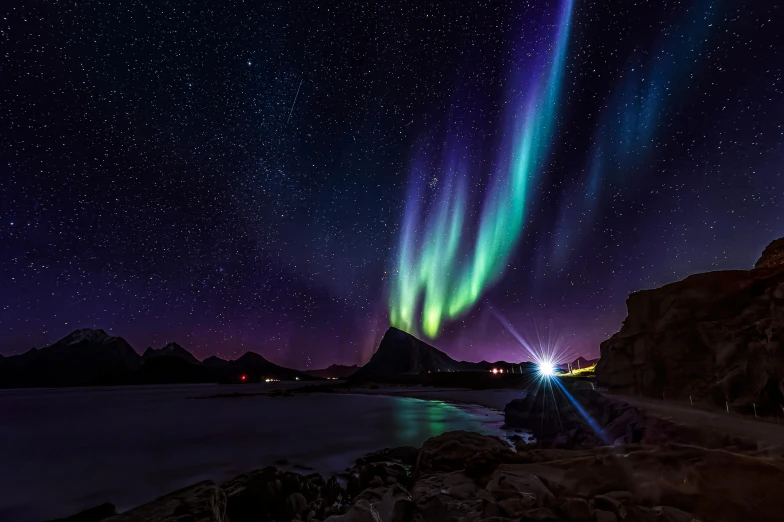 the aurora aurora is rising over a mountain and a body of water