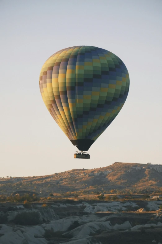 a large balloon is in the air above some mountains