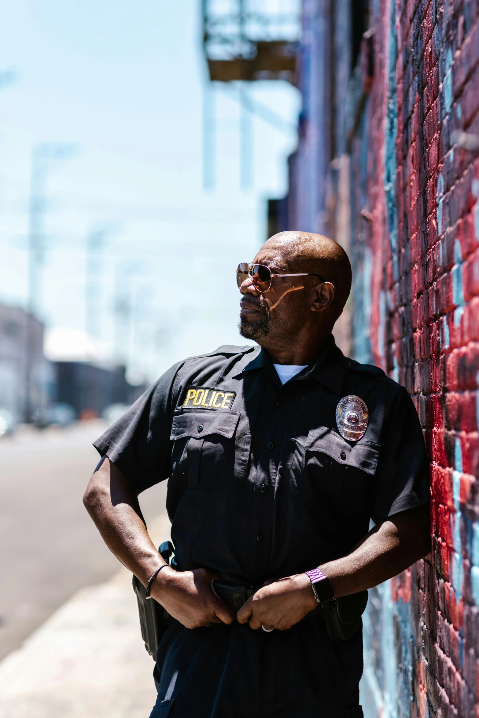 a police officer leaning up against a brick wall