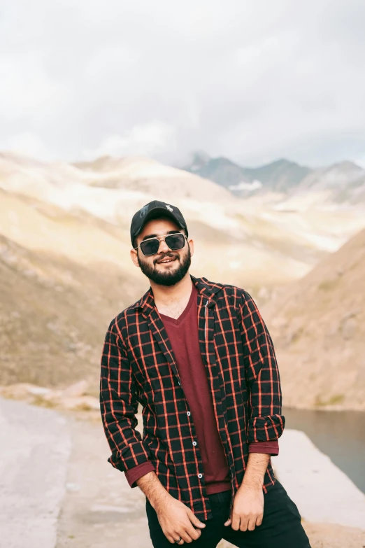 a man in plaid shirt standing next to mountains