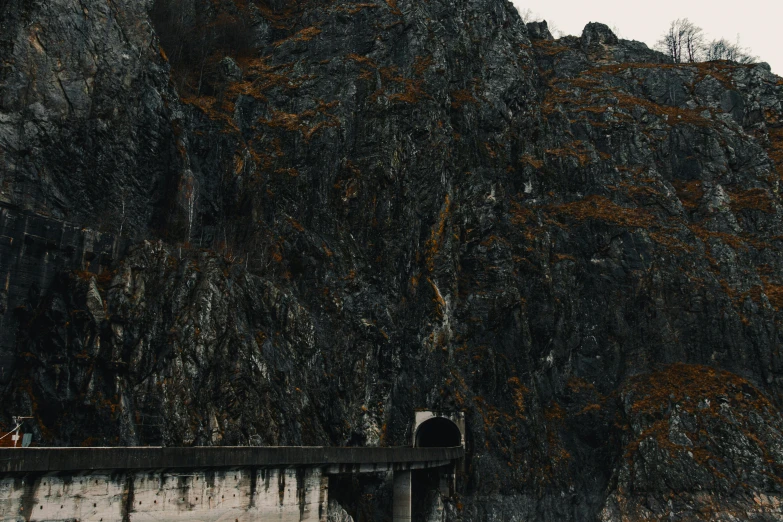 two people walking in front of the entrance to an area near a mountain