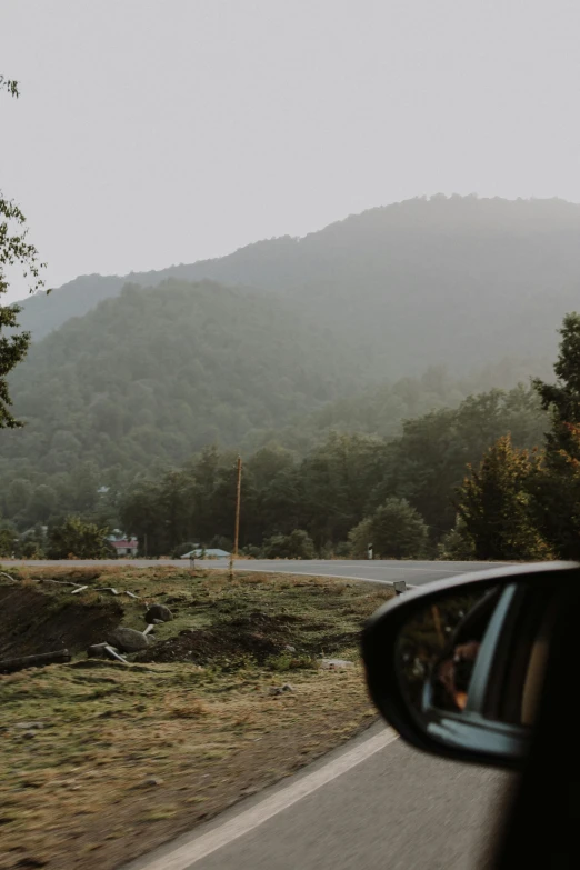 a car side view mirror sitting next to a scenic mountain range