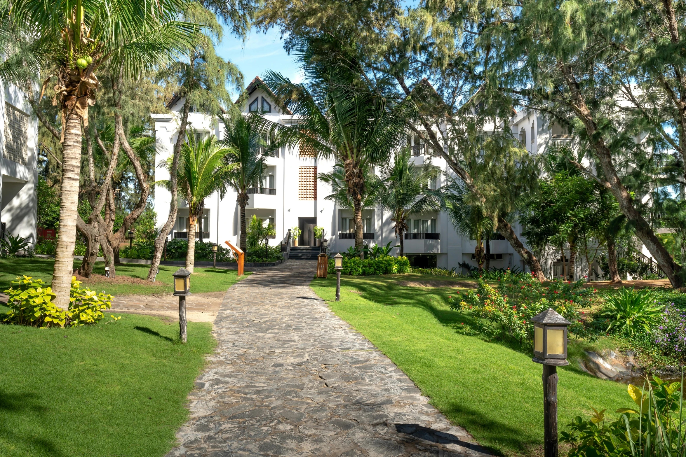 the white building has lots of trees in the yard