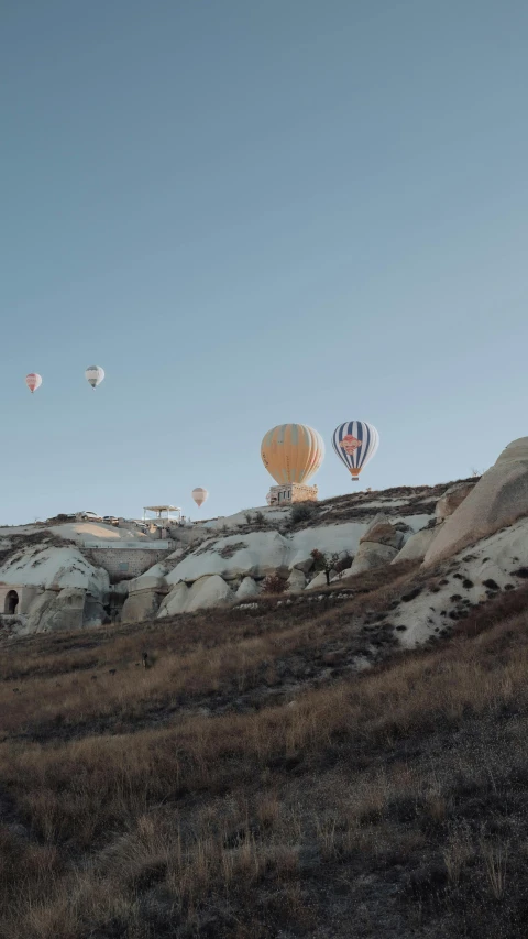 several  air balloons in the sky above some land