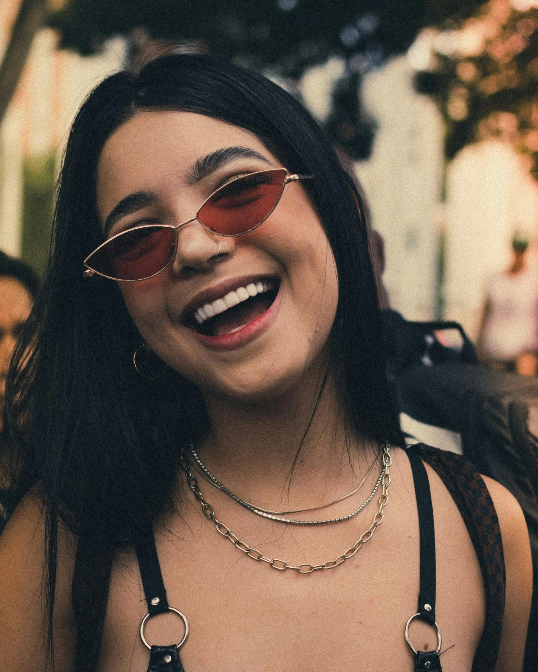 a smiling woman with sun glasses wearing black necklace and brown leather belt