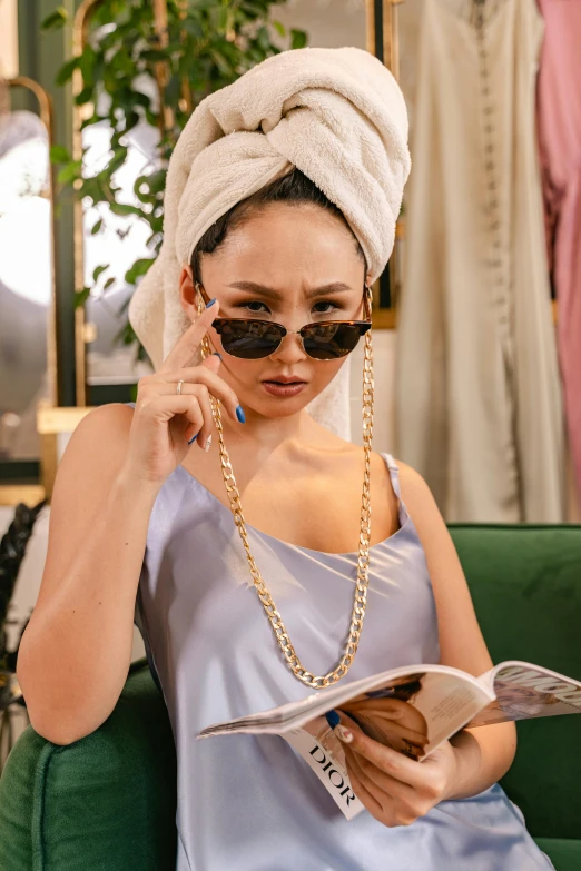 a beautiful young lady in a towel on her head reading a paper