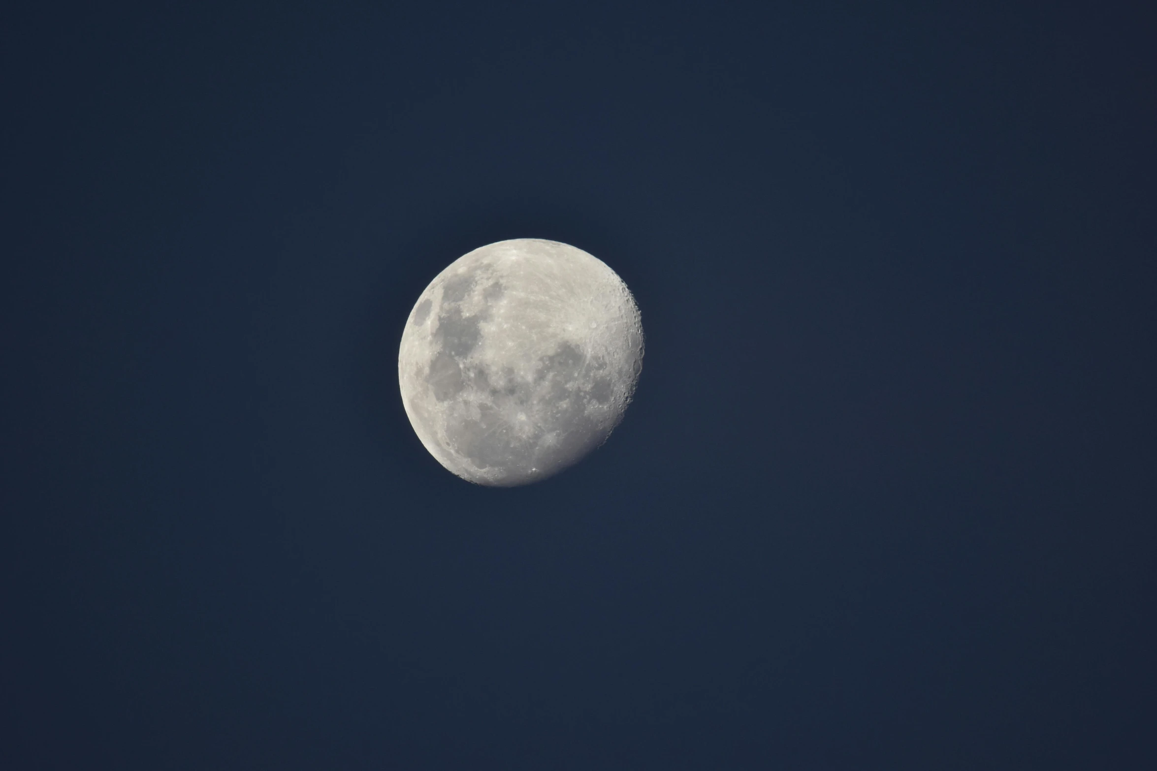 a full moon seen against a blue sky
