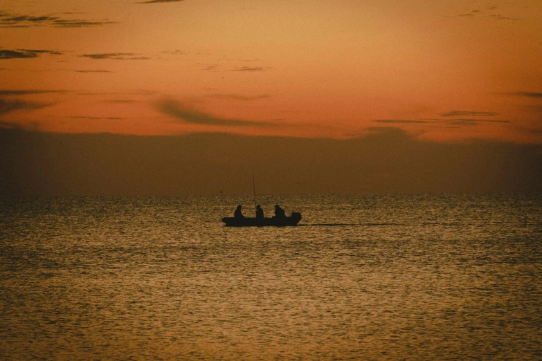 a boat in the middle of the ocean at sunset