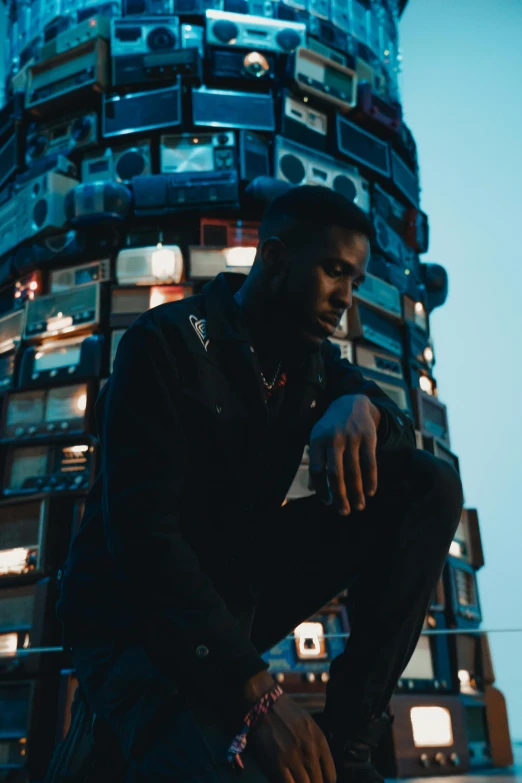 a black man with  posing by a tower of technology