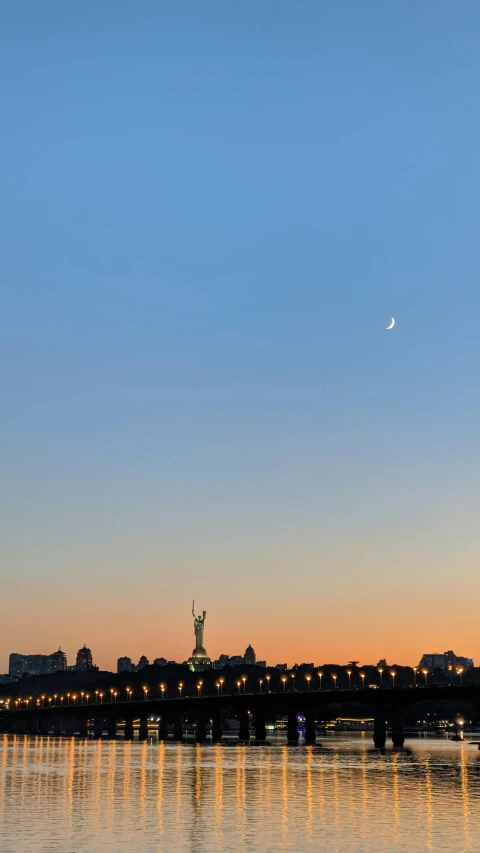 the sky over the river and bridge with a light house on top