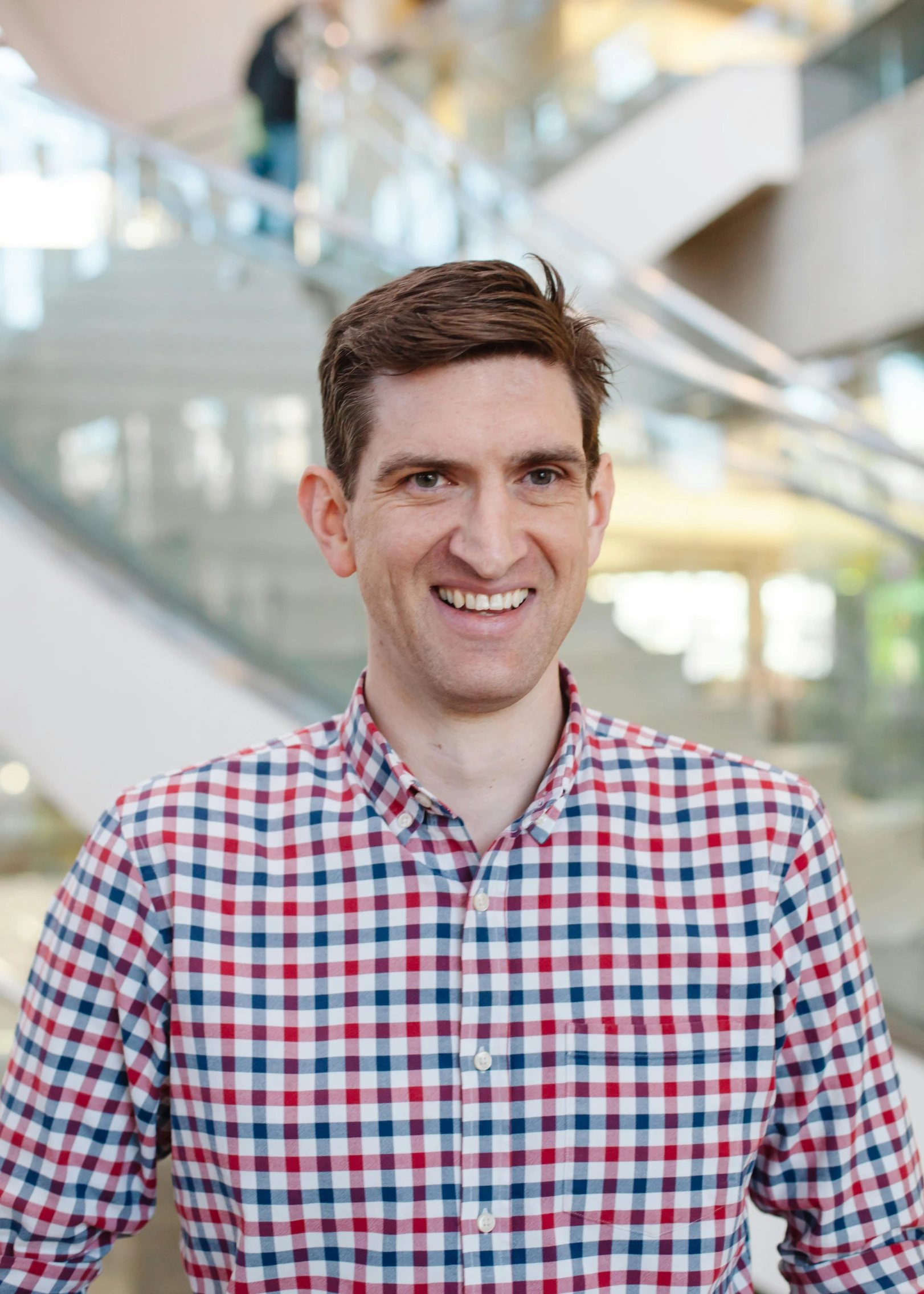 a man with a red, white and blue checked shirt is smiling