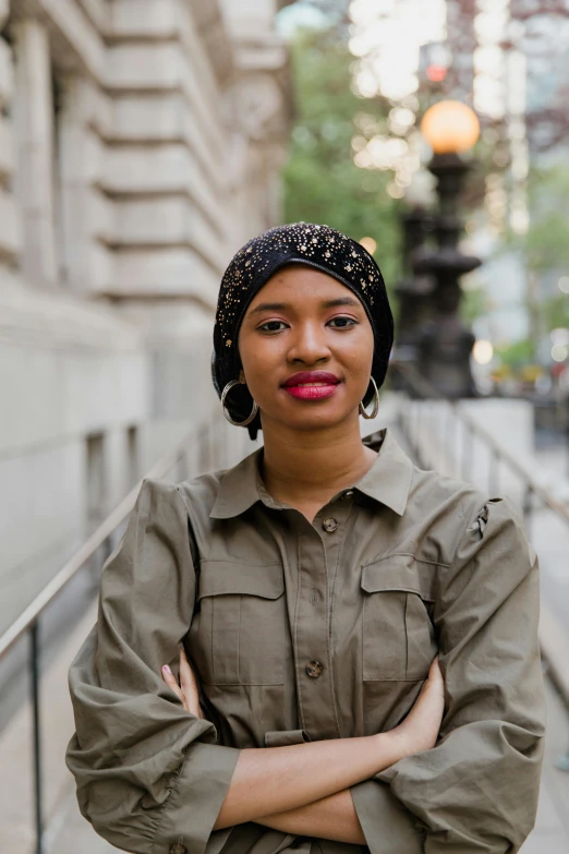 a woman is posing outside with her arms crossed