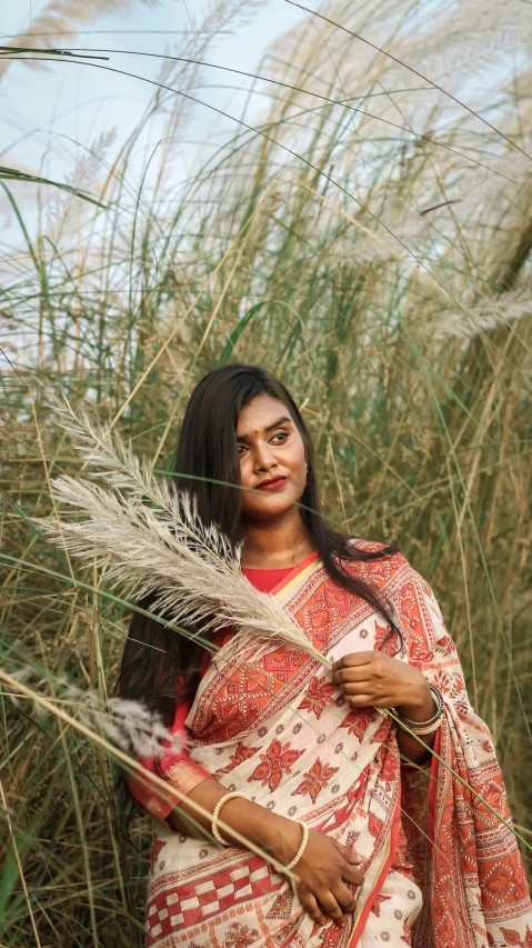 an indian woman in a sari walking in the tall grass