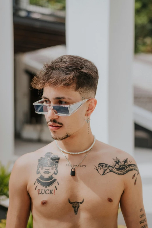 a shirtless man with tattoos and piercings wearing sunglasses