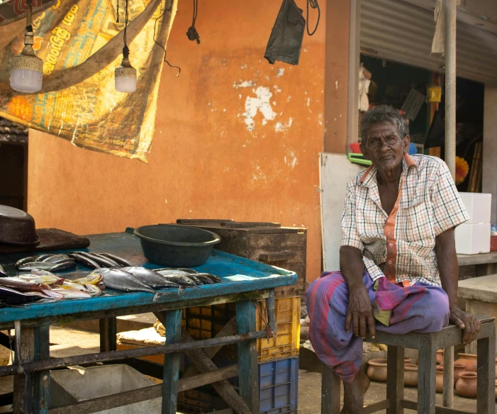 an old man sitting in a chair outside his shop