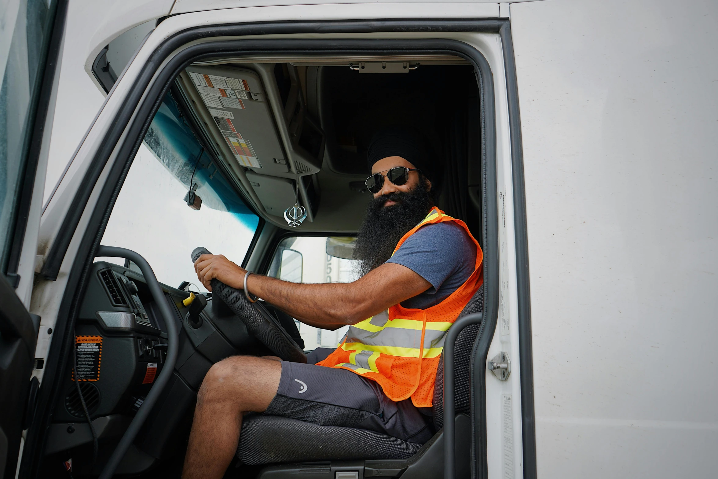 a man with a beard wearing sunglasses and a safety vest is driving