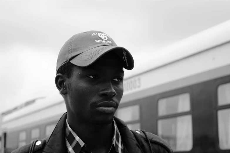 a man in a hat stands next to the train