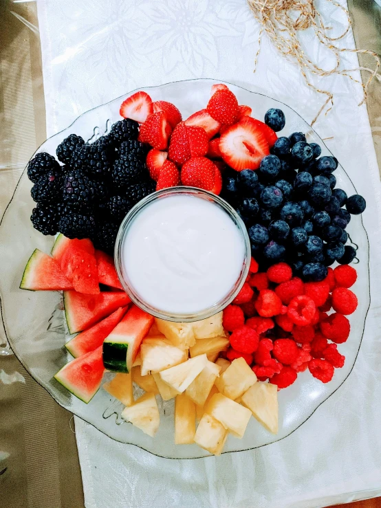 a tray full of cut up fruit and a cup with a dip in it