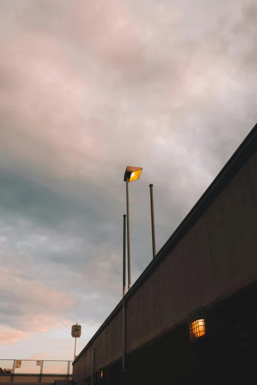 two street lights are on in a cloudy sky