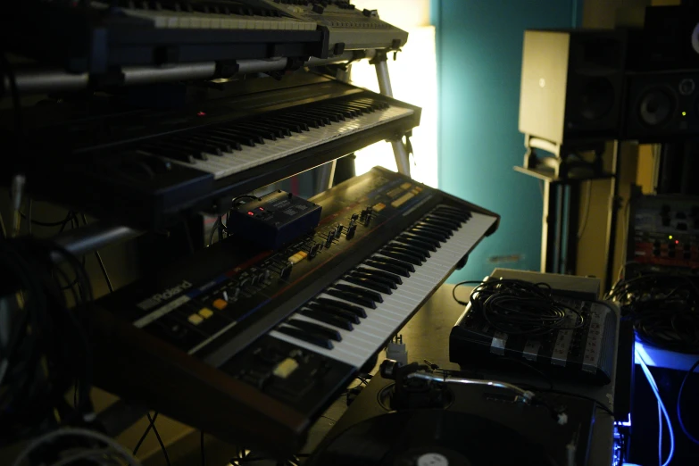 several keyboards sit near a large set of music equipment