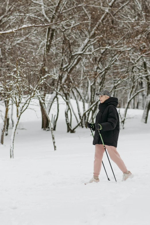 a woman in boots and winter clothes walking through the snow with ski poles