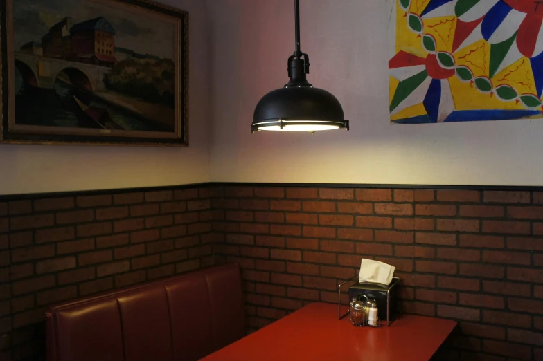 a red table with red benches and wall lighting above it