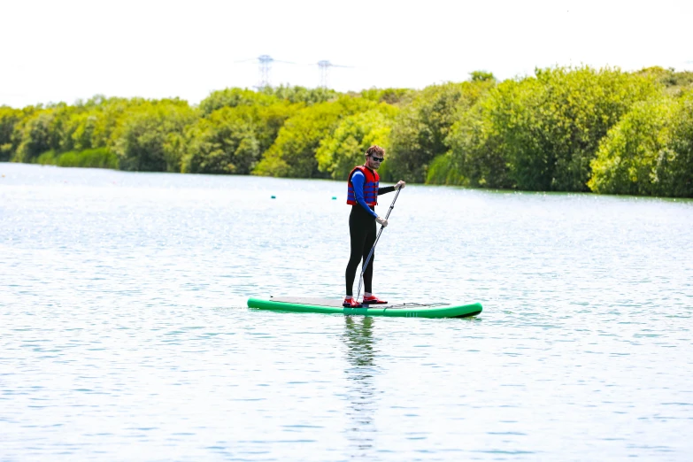 a person in a red and blue vest paddleboarding