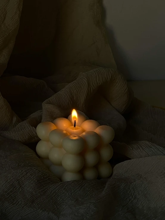 a lit candle on some kind of cloth
