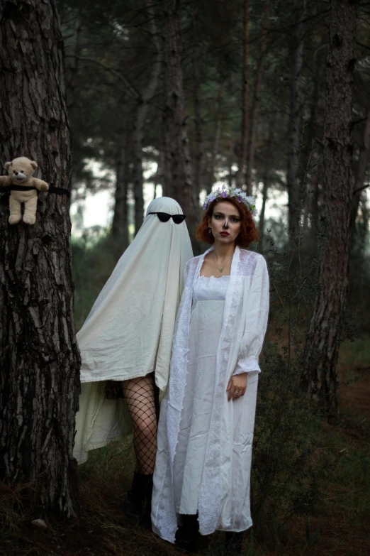 two people in white dress standing in the forest