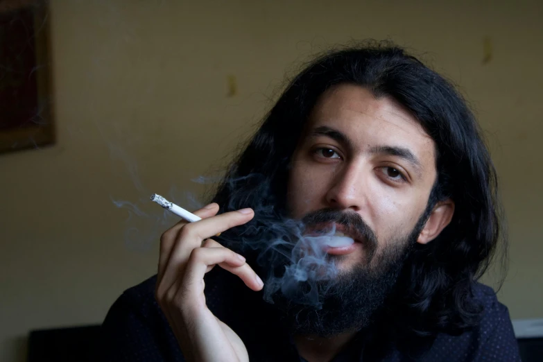 a man with long hair holding a cigarette