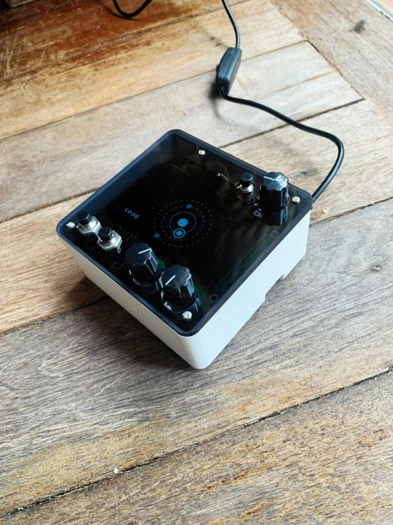 a black and white box on the ground with wires and some earplugs