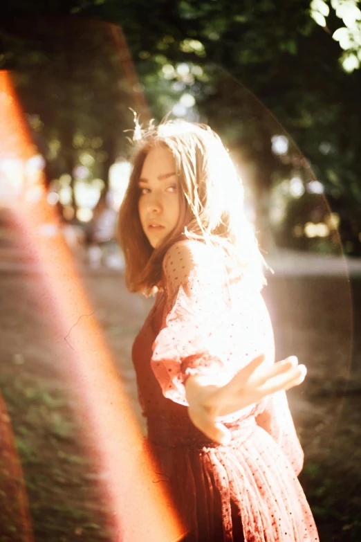 a woman in a dress standing by a tree