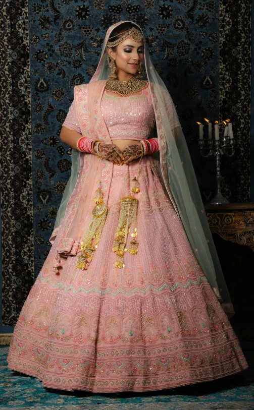 a bride in pink with gold jewelry in a traditional indian outfit