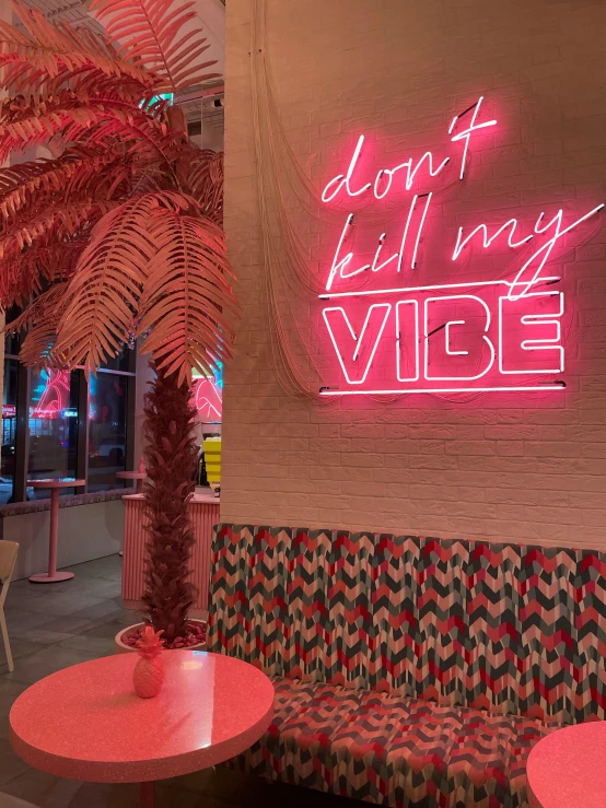 a pink neon sign on the wall near a table and a couch