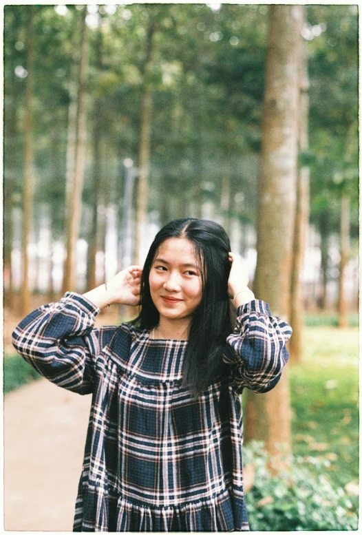 a woman poses in front of some trees