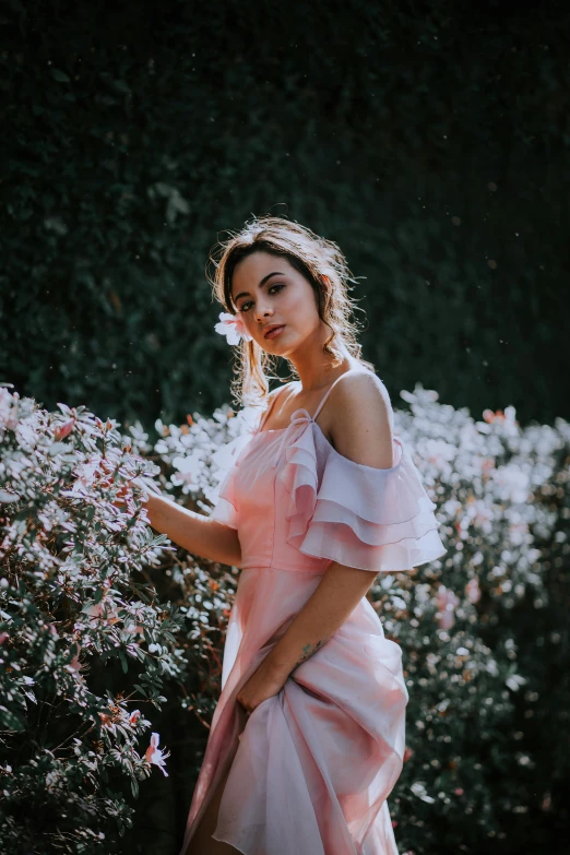 a young woman is in a pink dress holding onto a bush