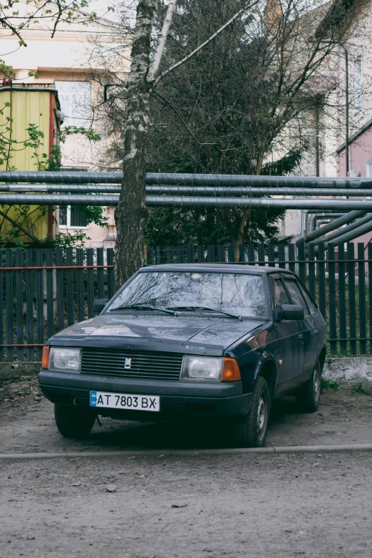 a small black car parked beside a fence