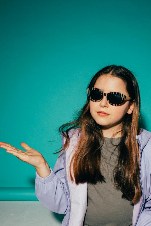 a girl wearing sunglasses while sitting on the ground