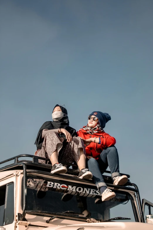 two people are sitting on top of a truck