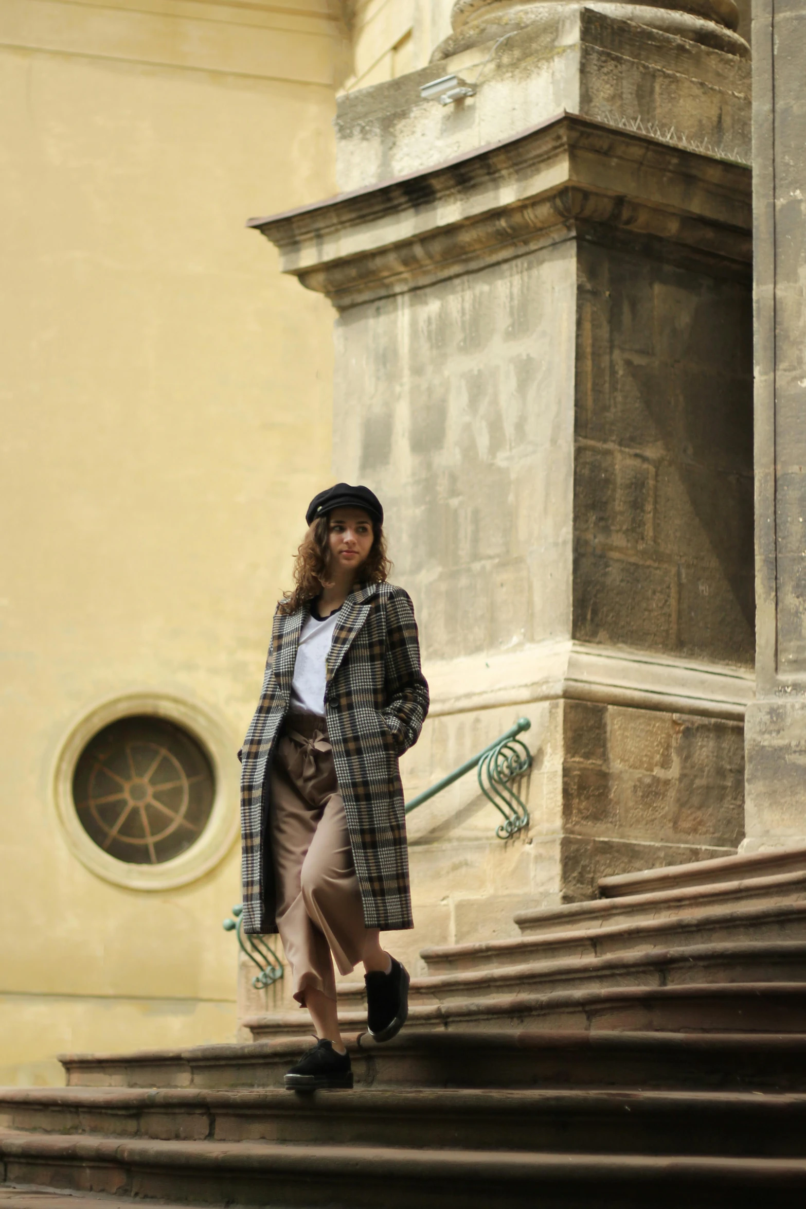 a woman in a plaid coat is posing on the steps
