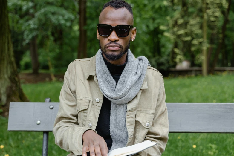 the man is sitting on the bench reading a book