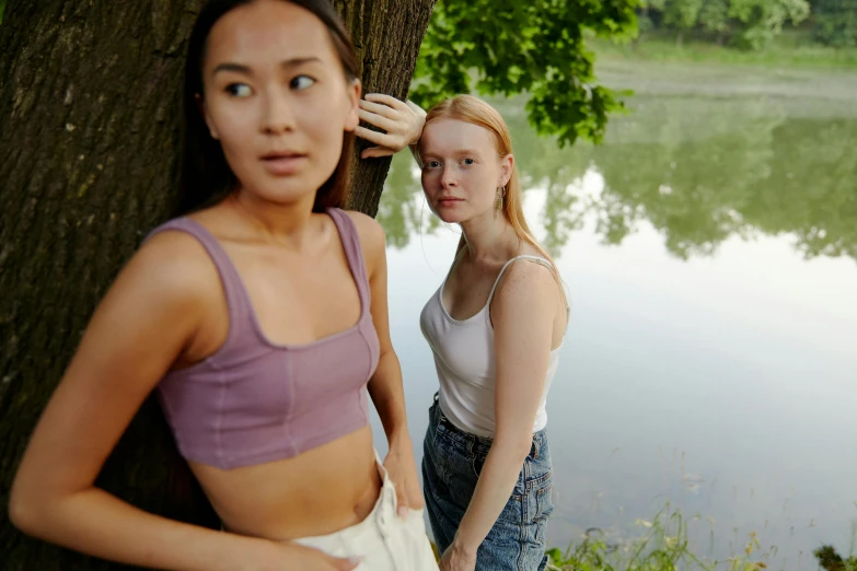 two young women standing by a lake with their bare 