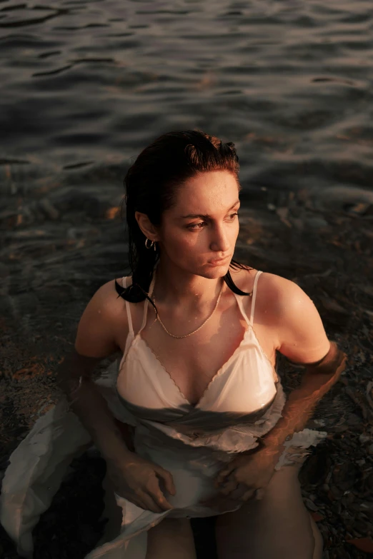 woman sitting in water, looking over body of water