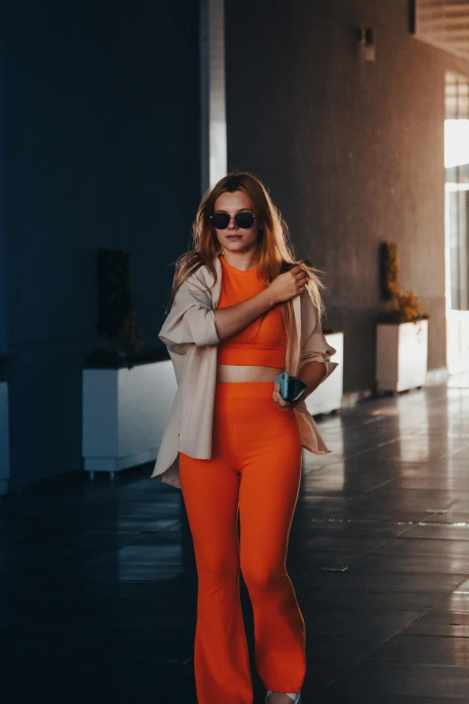 a person walking down a hallway wearing an orange outfit and carrying a purse