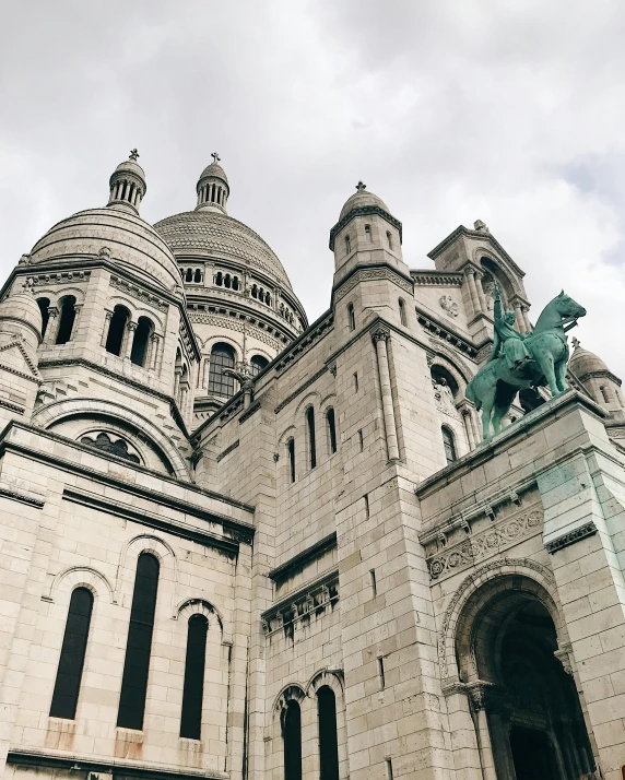 a tall white and gray church with a statue on top of it