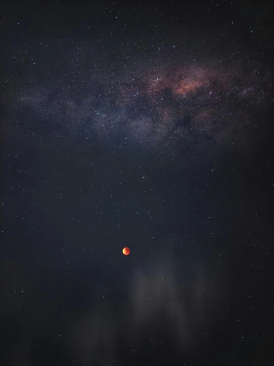 a red ball sitting on top of a dark ground