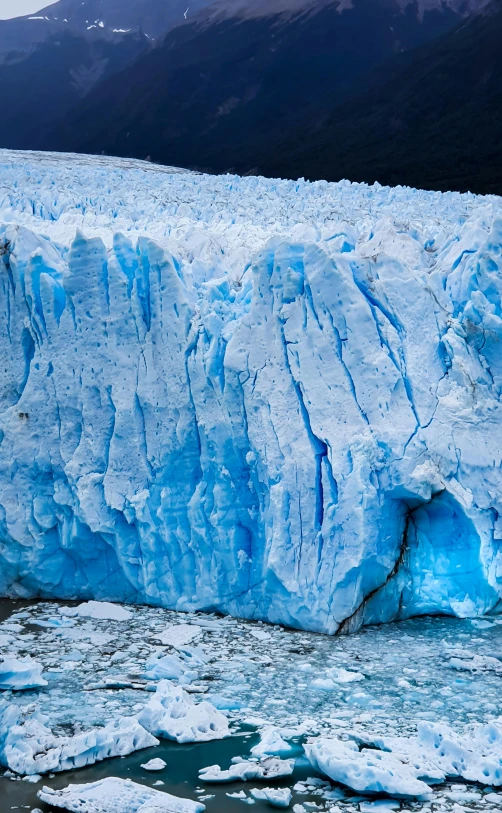 a glacier wall made of ice with a mountain in the background